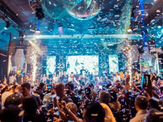 Vibrant nightclub scene in Mantua, Italy, featuring a lively crowd, confetti, and colorful lights.