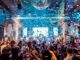 Vibrant nightclub scene in Mantua, Italy, featuring a lively crowd, confetti, and colorful lights.