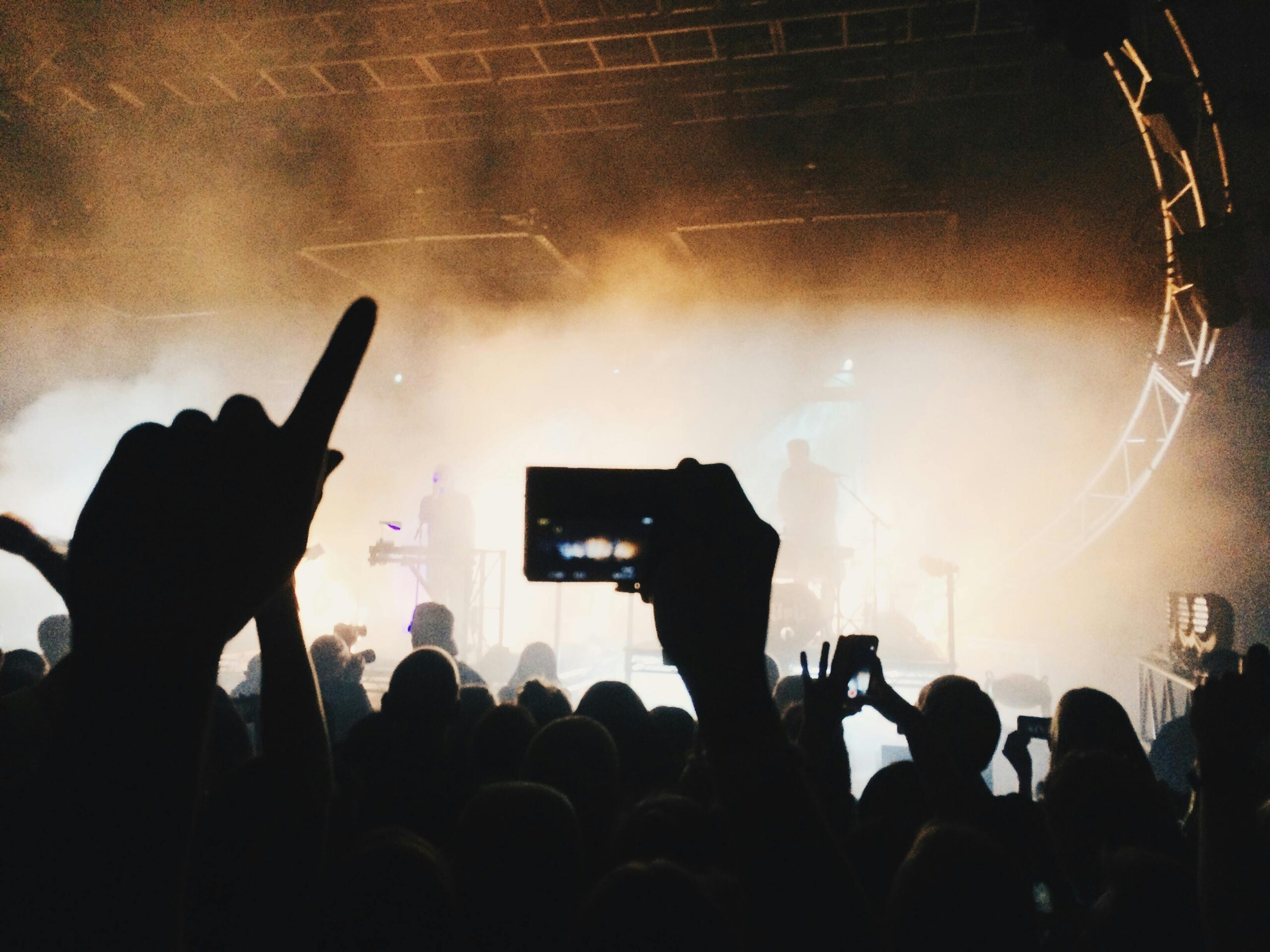 A vibrant concert scene with silhouettes of an energetic crowd capturing the moment on mobile phones.