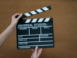 Close-up of hands holding a Universal Studios clapboard on a cork backdrop, ready for filming.
