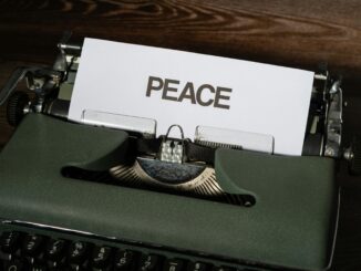 Close-up of a vintage typewriter with the word 'PEACE' typed on paper, conveying a serene message.
