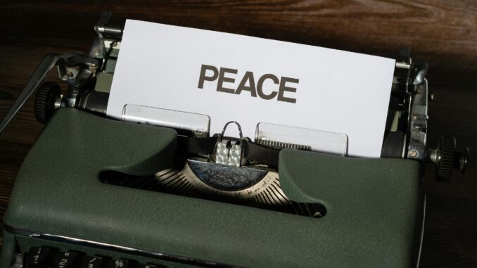 Close-up of a vintage typewriter with the word 'PEACE' typed on paper, conveying a serene message.