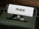 Close-up of a vintage typewriter with the word 'PEACE' typed on paper, conveying a serene message.