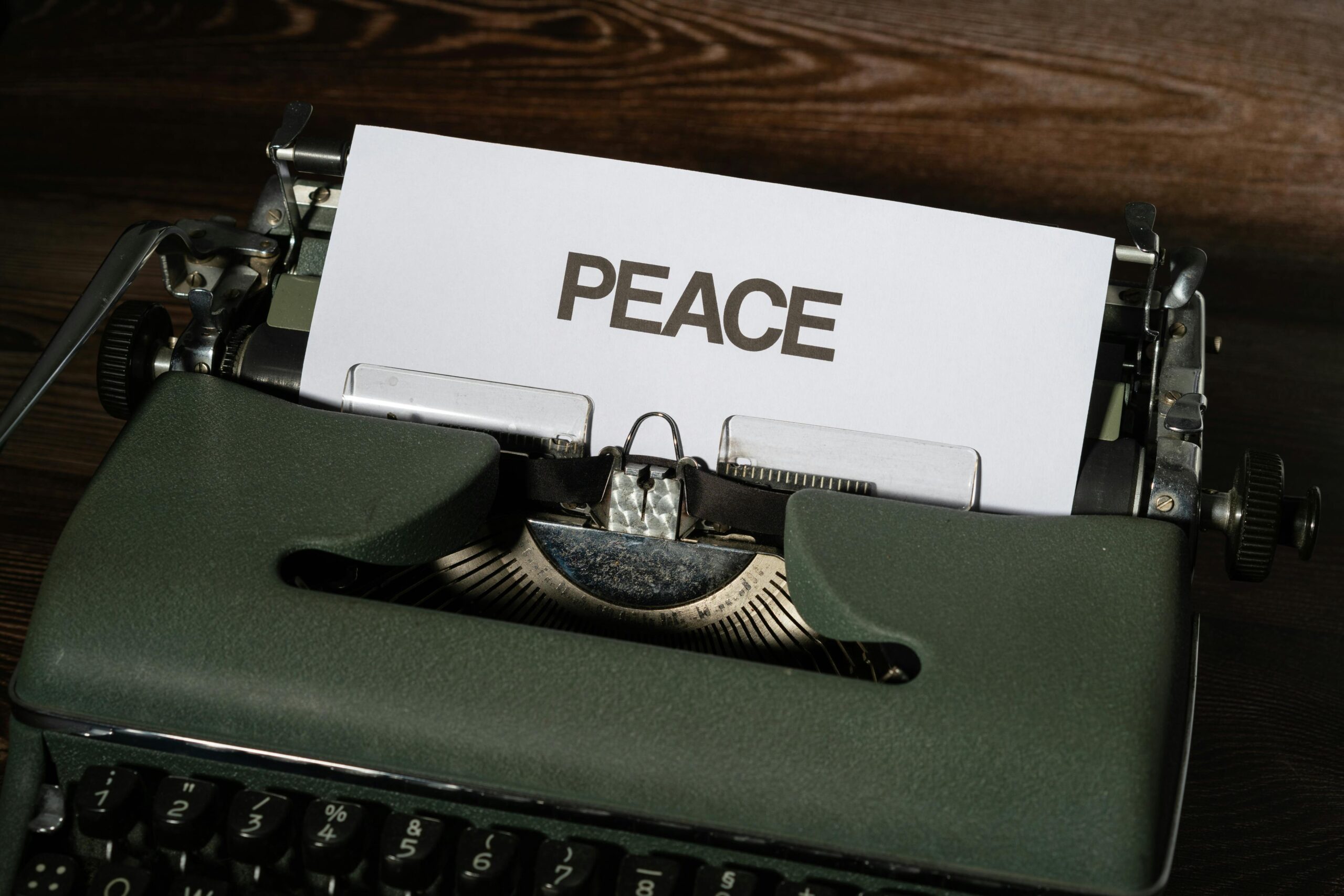 Close-up of a vintage typewriter with the word 'PEACE' typed on paper, conveying a serene message.