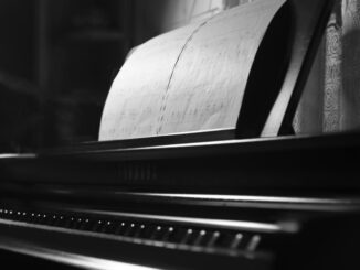 A monochrome photo of a piano with sheet music emphasizes elegance and musical artistry.