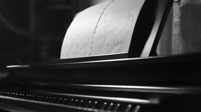 A monochrome photo of a piano with sheet music emphasizes elegance and musical artistry.