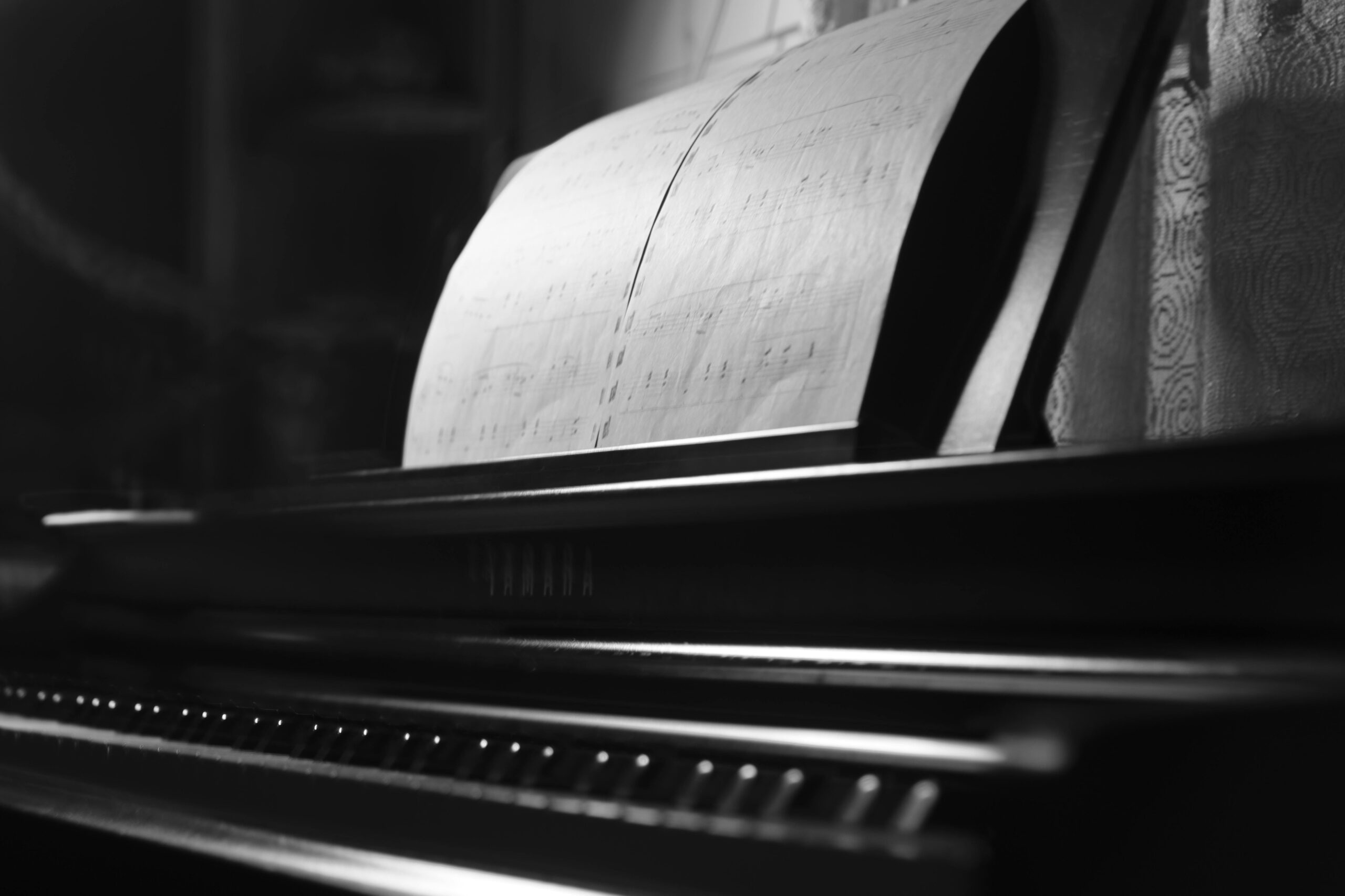 A monochrome photo of a piano with sheet music emphasizes elegance and musical artistry.