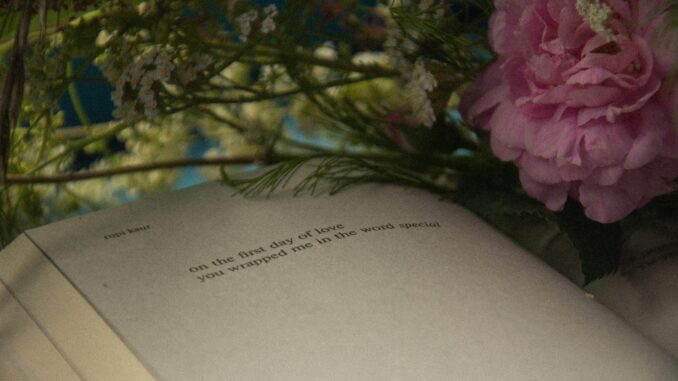 Open book surrounded by delicate flowers, creating a serene still life scene.