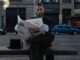 A stylish man in formal attire reads a newspaper on a bench in Buenos Aires.