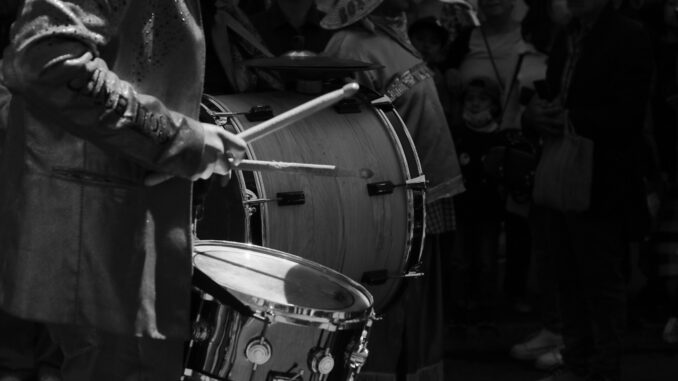 Black and white image of a drummer in a parade, creating rhythm in Pachuca de Soto.