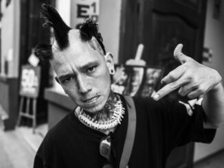 Black and white street portrait of a punk enthusiast with unique hairstyle and tattoos.