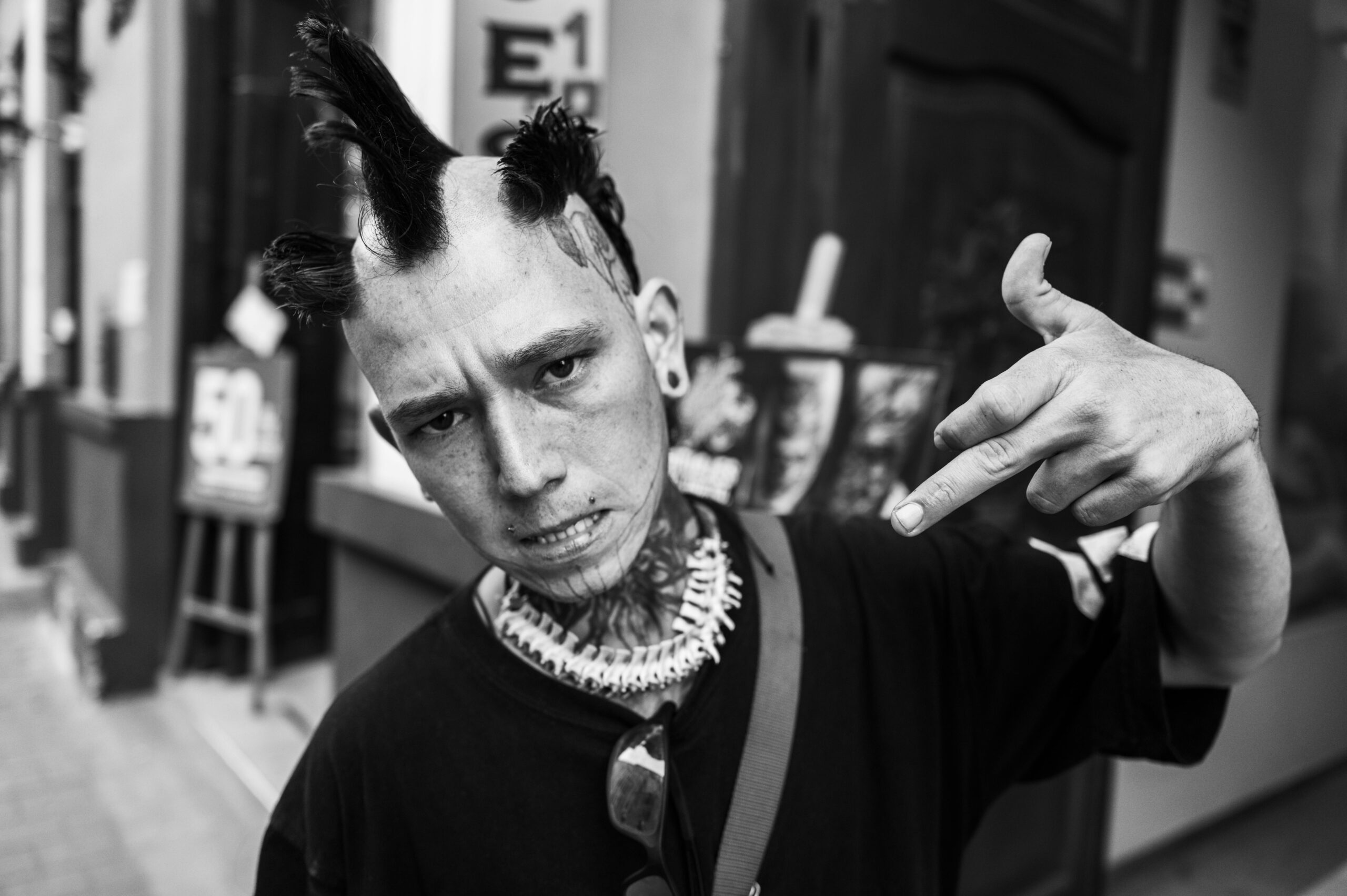 Black and white street portrait of a punk enthusiast with unique hairstyle and tattoos.