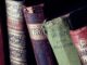 Close-up of vintage leather-bound books with ornate designs on a bookshelf.