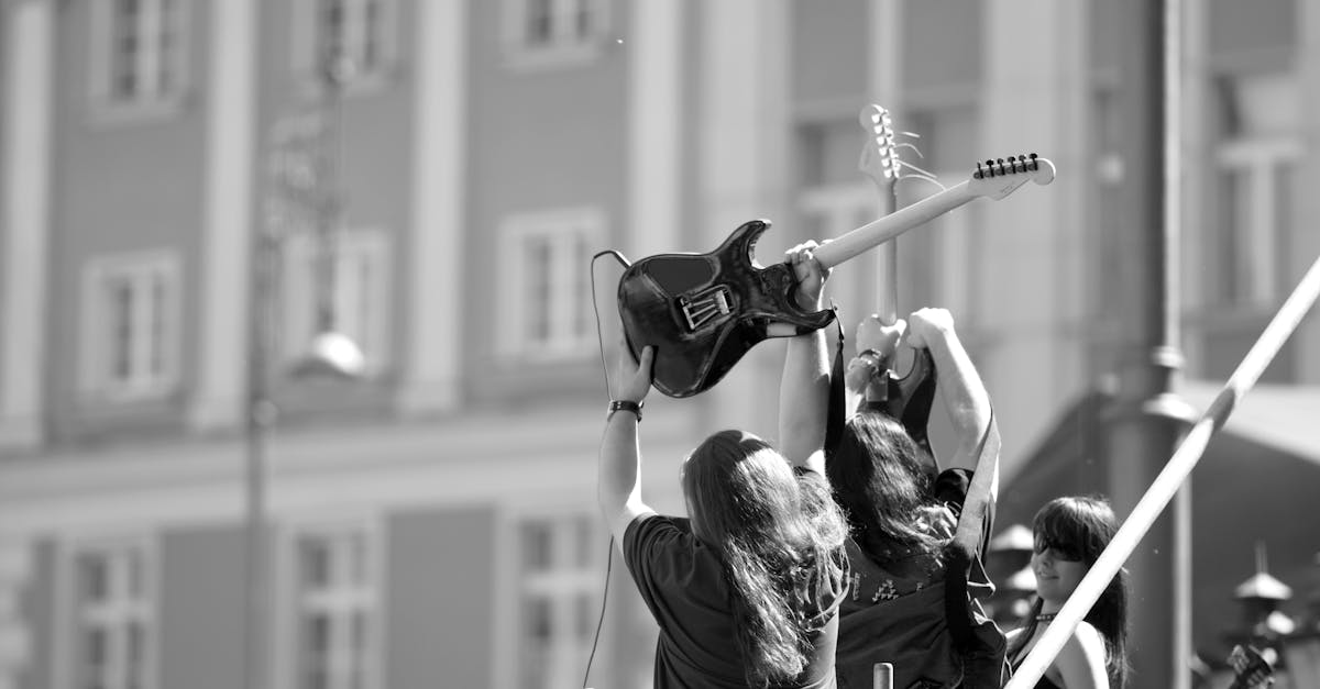 Dynamic black and white photo of musicians with guitars at an outdoor concert.