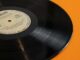 A classic vinyl record displayed against a bright yellow backdrop, embodying retro nostalgia.