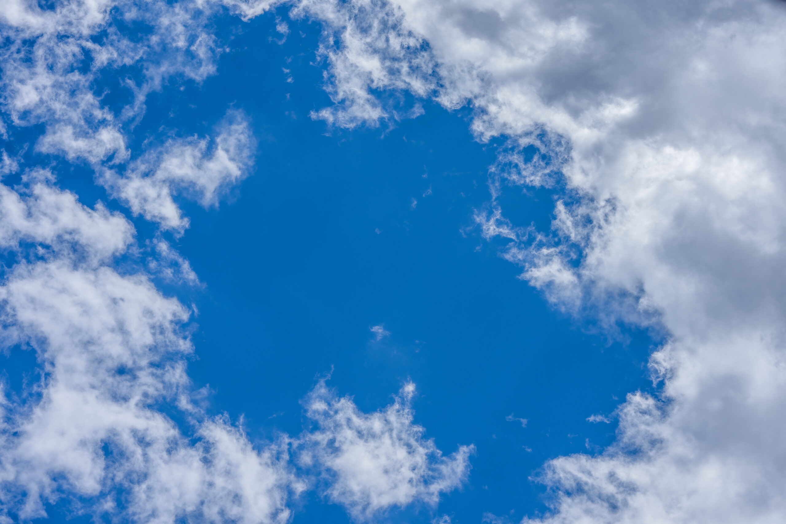 Vibrant blue sky with scattered fluffy white clouds, perfect for backgrounds or wallpapers.