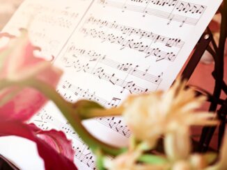 Close-up of sheet music surrounded by beautiful flowers, creating an artistic and serene still life.