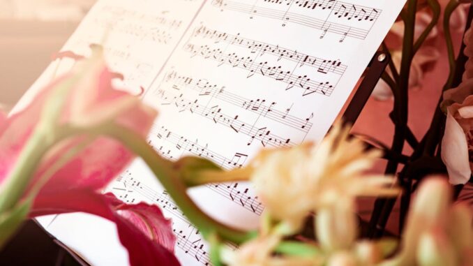 Close-up of sheet music surrounded by beautiful flowers, creating an artistic and serene still life.