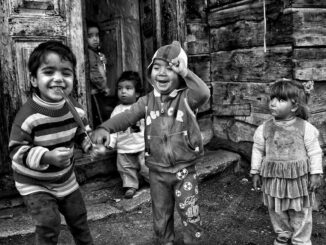 Joyous children playing on a rustic porch, captured in black and white.