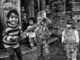 Joyous children playing on a rustic porch, captured in black and white.