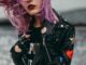 Stylish woman with purple hair in a studded leather jacket. Edgy and modern fashion.