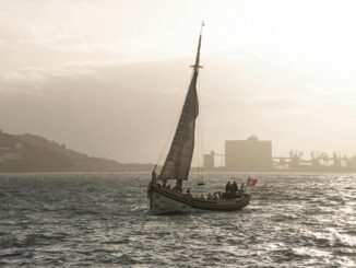 Elegant sailboat gliding across Lisbon's waters during a serene sunset.