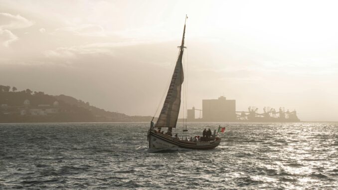 Elegant sailboat gliding across Lisbon's waters during a serene sunset.