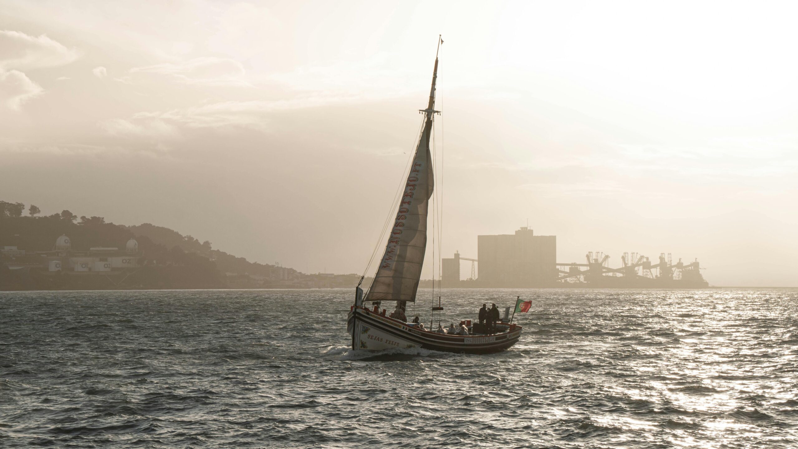Elegant sailboat gliding across Lisbon's waters during a serene sunset.