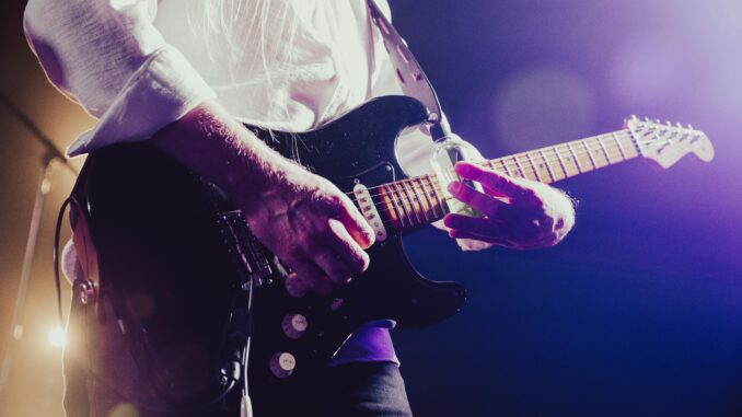 Close-up of a musician passionately playing an electric guitar under stage lights.