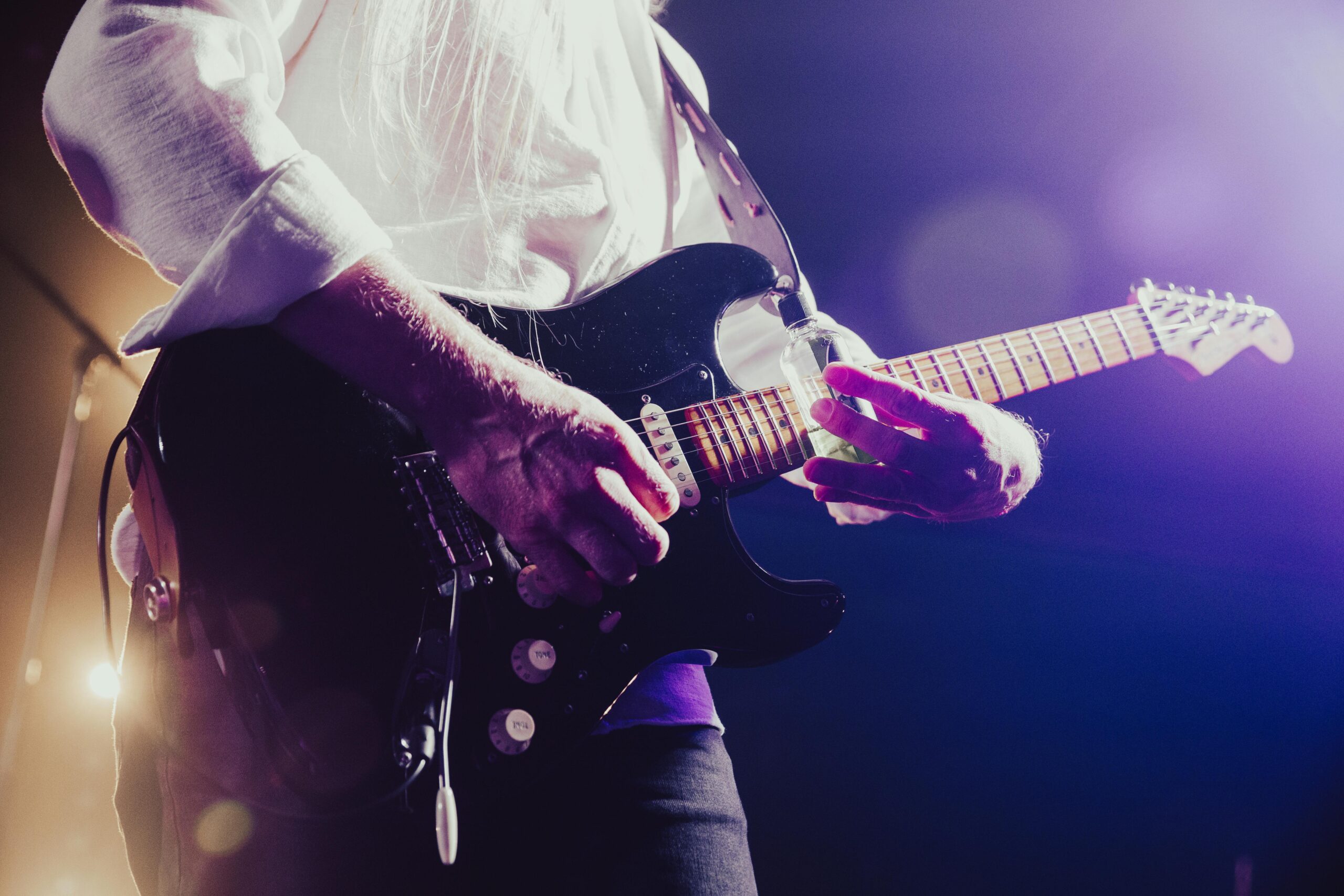 Close-up of a musician passionately playing an electric guitar under stage lights.