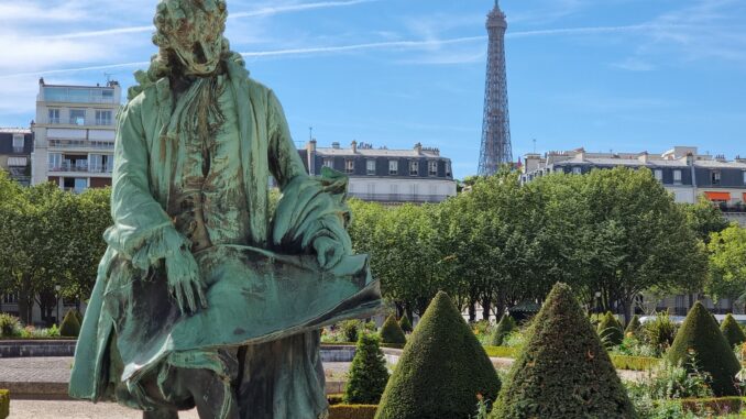 Elegant statue in Paris garden with Eiffel Tower in the background on a sunny day.