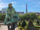 Elegant statue in Paris garden with Eiffel Tower in the background on a sunny day.