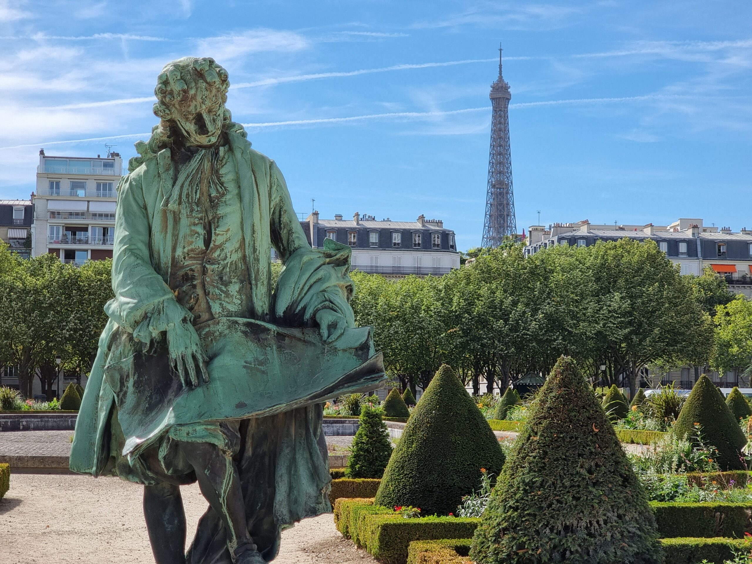 Elegant statue in Paris garden with Eiffel Tower in the background on a sunny day.