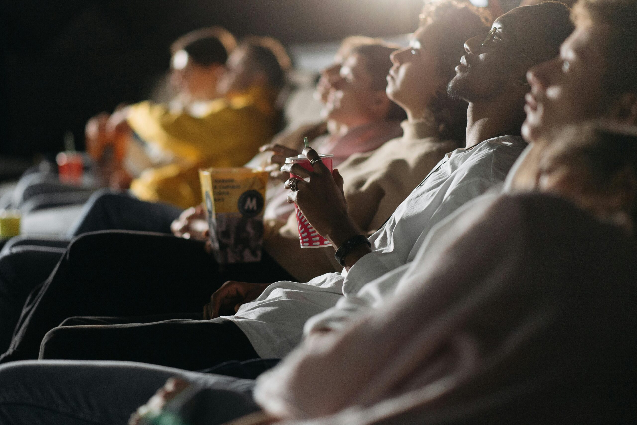 Group of friends watching a film in a cinema, sharing a fun movie night experience.