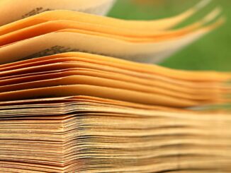 Macro shot of aged book pages with a blurred green background, highlighting texture and detail.