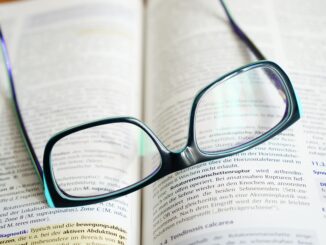 Reading glasses resting on an open textbook, symbolizing study and knowledge.