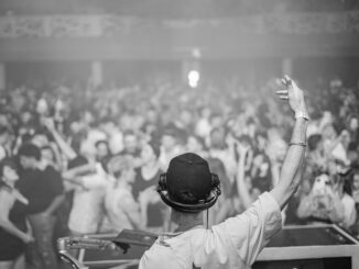 DJ in control, hyping up a large crowd at a lively nightclub event, creating an electrifying atmosphere.