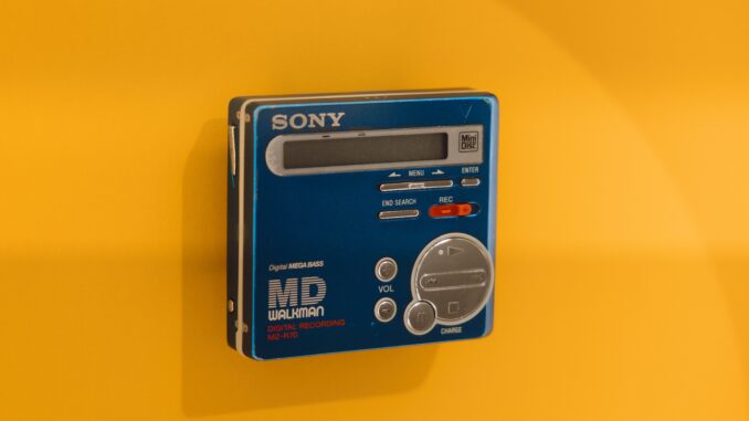 A classic Sony MD Walkman displayed against a vivid yellow backdrop, highlighting retro tech charm.