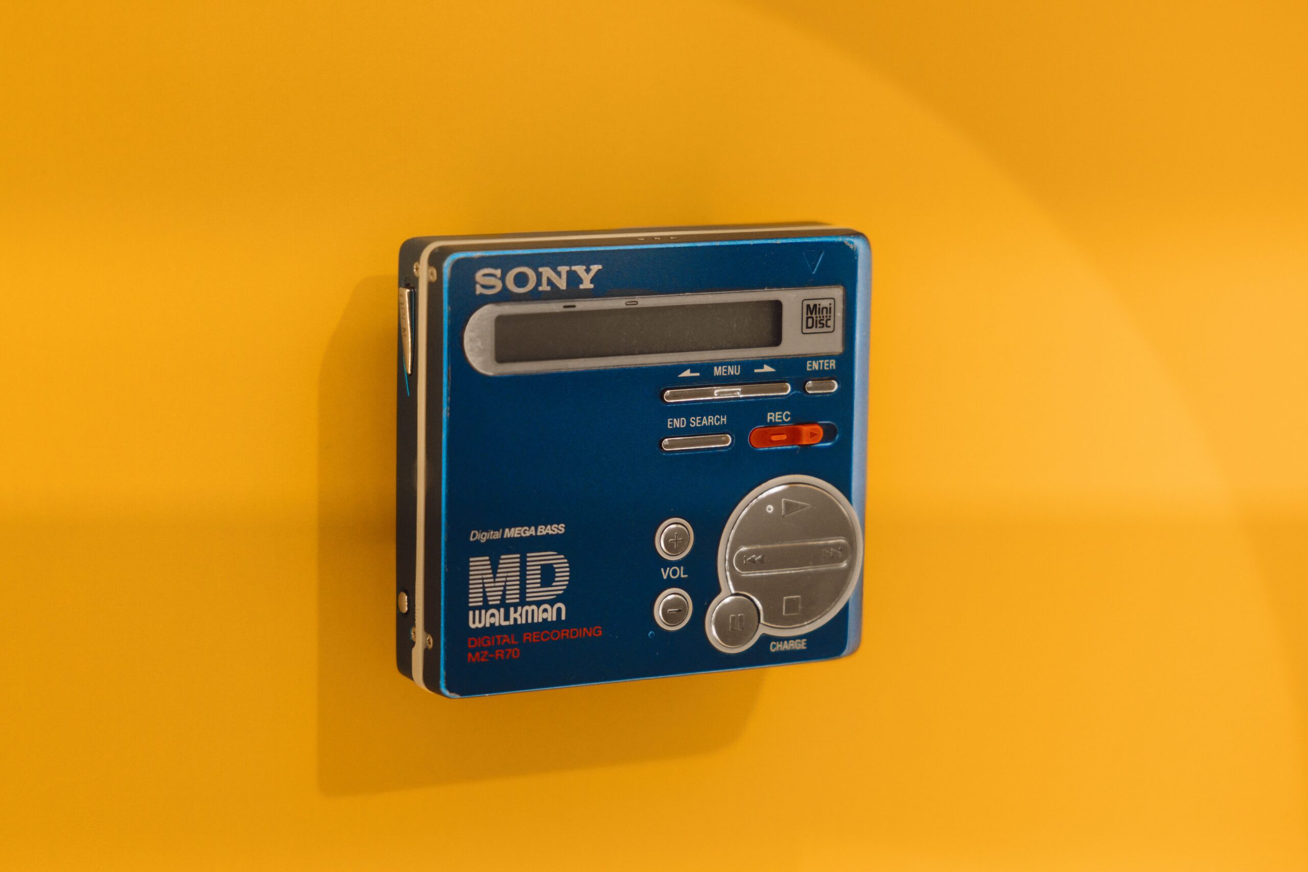 A classic Sony MD Walkman displayed against a vivid yellow backdrop, highlighting retro tech charm.