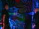 Two individuals celebrating street style in a graffiti-lit room under neon lights.