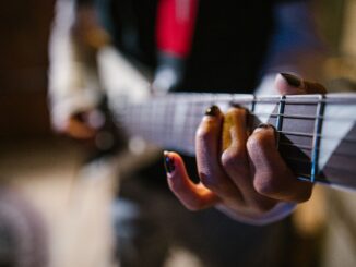Focused hands of a musician strumming an electric guitar in a dynamic music approach.