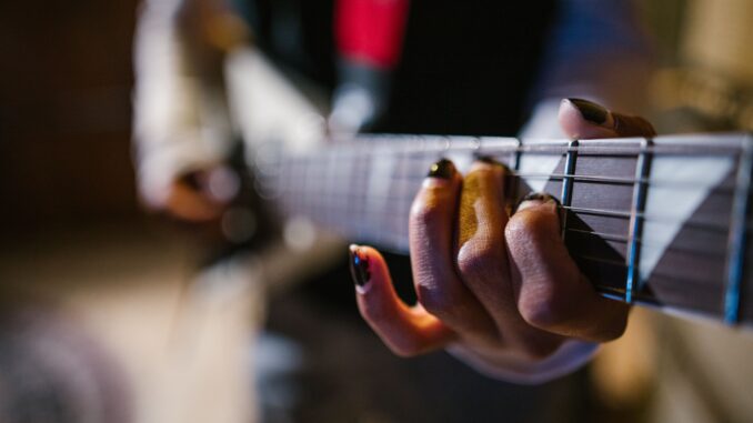 Focused hands of a musician strumming an electric guitar in a dynamic music approach.
