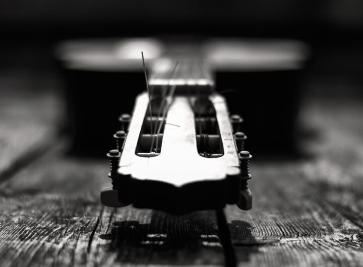 Close-up of a guitar's headstock with strings, in black and white.