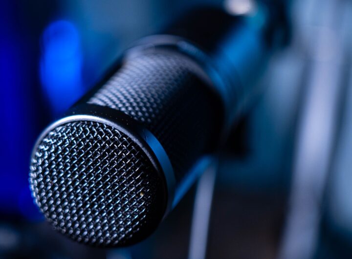 Detailed close-up of a professional studio microphone with a blurred blue background.