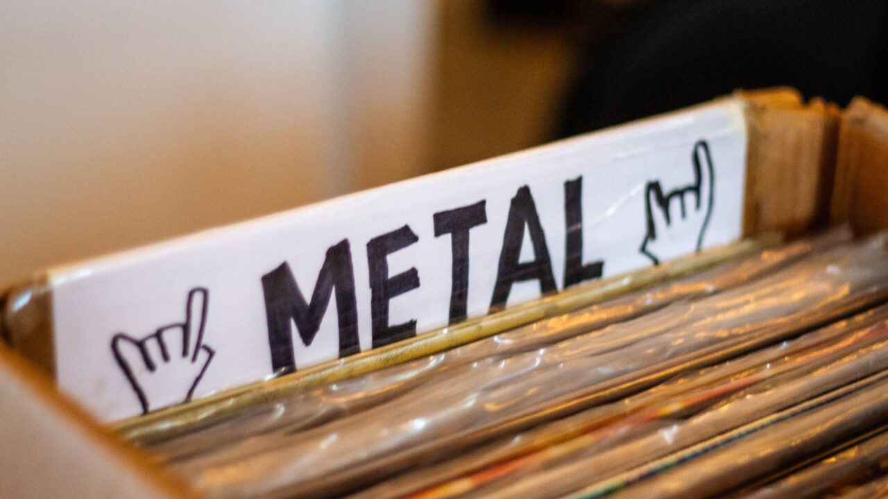 A detailed view of a box filled with metal genre vinyl records at a music store.