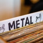 A detailed view of a box filled with metal genre vinyl records at a music store.