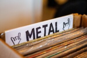 A detailed view of a box filled with metal genre vinyl records at a music store.