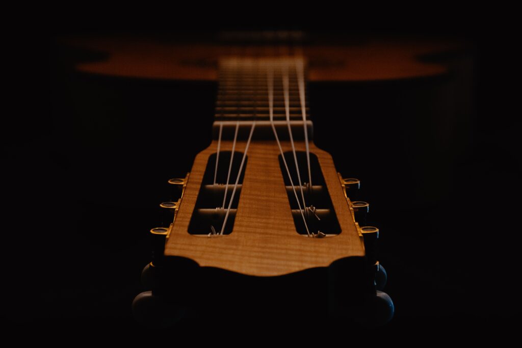 Artistic close-up of a classical guitar's strings and headstock captured in low light ambiance.