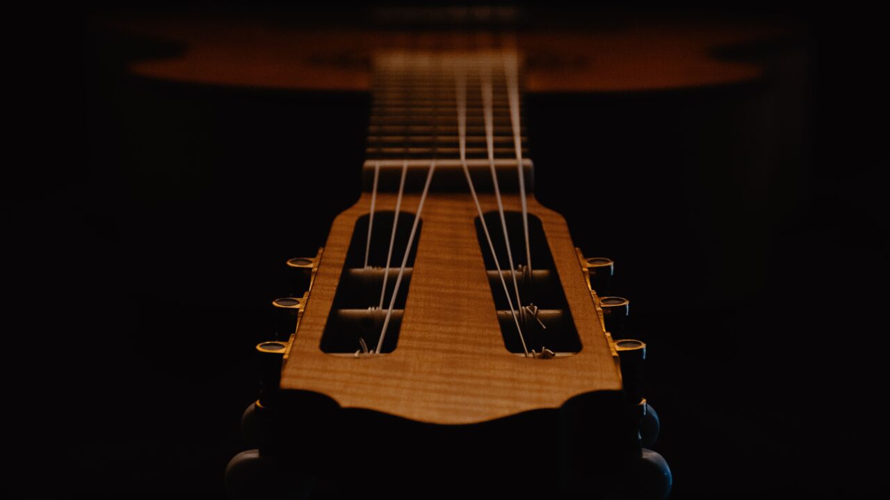 Artistic close-up of a classical guitar's strings and headstock captured in low light ambiance.