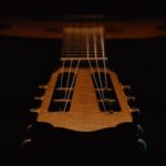 Artistic close-up of a classical guitar's strings and headstock captured in low light ambiance.